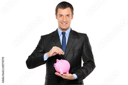 Photo: Businessman putting a coin into a piggy bank Businessman putting a coin into a piggy bank