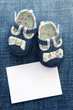 Baby shoes and blank note on blue background