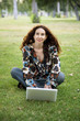 Foto: woman, wearing a hearing aid, working on her laptop in a park. woman, wearing a hearing aid, working on her laptop in a park.