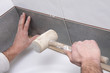 mains posant carrelage avec maillet