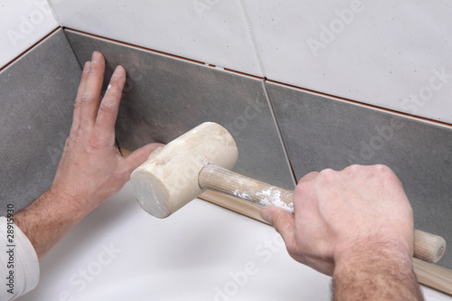 Photo: mains posant carrelage avec maillet mains posant carrelage avec maillet