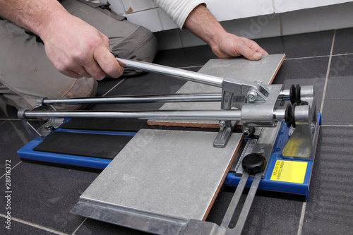 Photo: mains découpant carrelage avec machine mains découpant carrelage avec machine