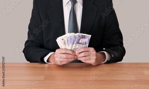 Photo: Man in suit sitting with cash - pounds sterling Man in suit sitting with cash - pounds sterling