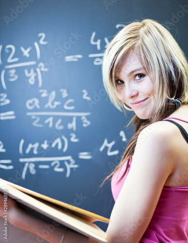 Photo: pretty young college student writing on the chalkboard pretty young college student writing on the chalkboard