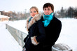 Happy couple in winter park standing on a bridge