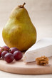 Green pear, cheese brie, walnut, grapes on wooden board macro