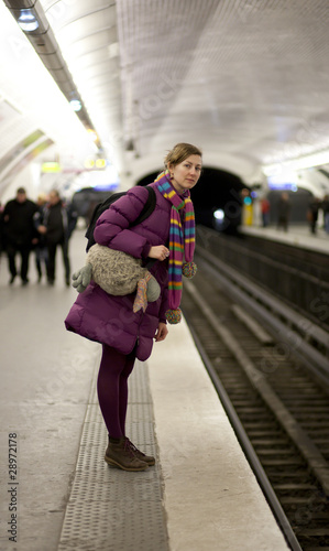Photo: Tourist girl in bright clothes and funny bag waiting for the tra Tourist girl in bright clothes and funny bag waiting for the tra