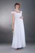 young pregnant bride wearing wedding gown in studio