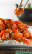 sweet and sour pork on rice being eaton with chopsticks