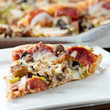 slice of pizza on a plate with pereroni and black olives