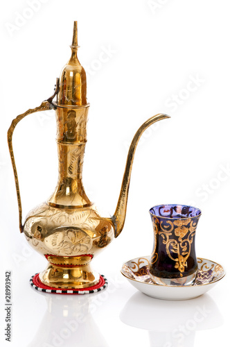 Photo: Arabic brass coffee pot with a welcoming a cup full of coffee. Arabic brass coffee pot with a welcoming a cup full of coffee.