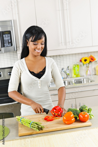 Photo: Young woman cutting vegetables in kitchen Young woman cutting vegetables in kitchen
