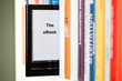e-book reader schaut zwischen büchern hervor