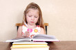 Little girl reading book in the kitchen against yellow wall at h