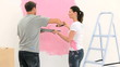 Happy couple painting a wall in pink