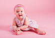 Portrait of the small joyful girl on a pink background