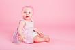 Portrait of the small beautiful joyful girl on a pink background