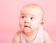Portrait of the small surprised girl on a pink background