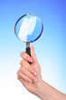 Magnifying glass in woman hand on blue background