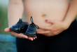 Pregnant girl and black baby shoes in front of it Pregnant girl and black baby shoes in front of it