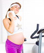Photo: Pregnant woman wiping face with towel after training on bicycle. Pregnant woman wiping face with towel after training on bicycle.