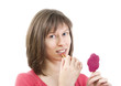 Young woman applying lipstick looking at mirror