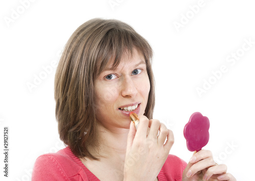 Foto: Young woman applying lipstick looking at mirror Young woman applying lipstick looking at mirror