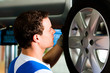 Foto: Car mechanic in workshop changing tire Car mechanic in workshop changing tire