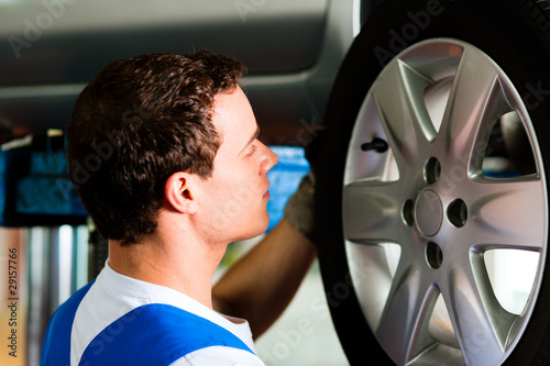 Photo: Car mechanic in workshop changing tire Car mechanic in workshop changing tire