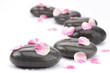 Spa stones with rose petals on white background.