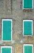 Closed green window shutters on a gray house facade