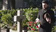 Mourning Man Standing on a Grave at the Cemetery