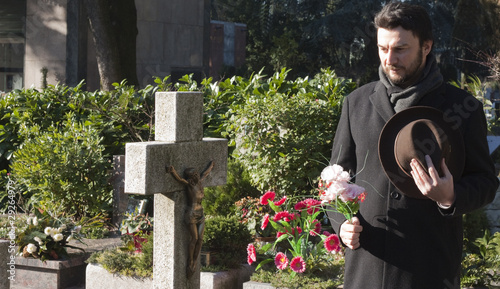 Photo: Mourning Man Standing on a Grave at the Cemetery Mourning Man Standing on a Grave at the Cemetery