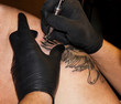 Tattoo master tattooing in the tattoo salon.