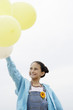 Smiling Pre-teen standing, arms raised, Holding Balloons