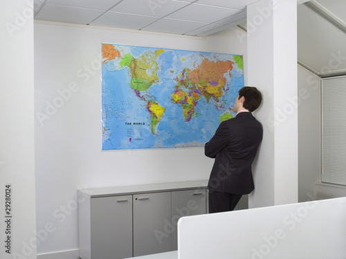 Foto: Businessman studying world map in office Businessman studying world map in office