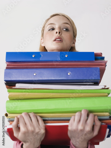 Photo: Female office worker carrying heavy binders, close-up Female office worker carrying heavy binders, close-up