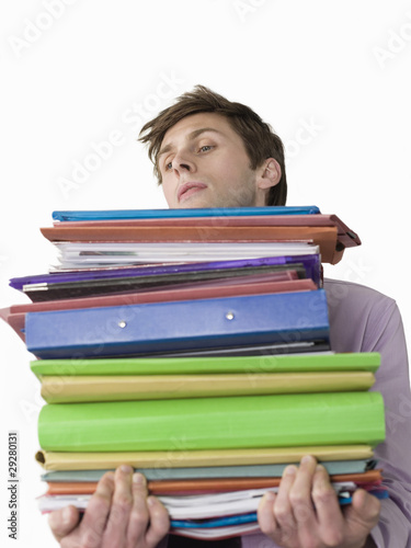 Photo: Male office worker carrying heavy binders, close-up Male office worker carrying heavy binders, close-up