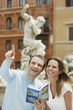 Photo: Young couple with guidebook looking at monuments on street in Rome, Italy, head and shoulders Young couple with guidebook looking at monuments on street in Rome, Italy, head and shoulders