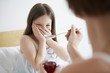 Mother giving cough syrup to reluctant daughter in bedroom