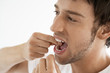 Photo: Mid-adult man flossing teeth in bathroom, close up Mid-adult man flossing teeth in bathroom, close up