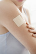 Woman looking at nicotine patch on arm, mid-section, close up