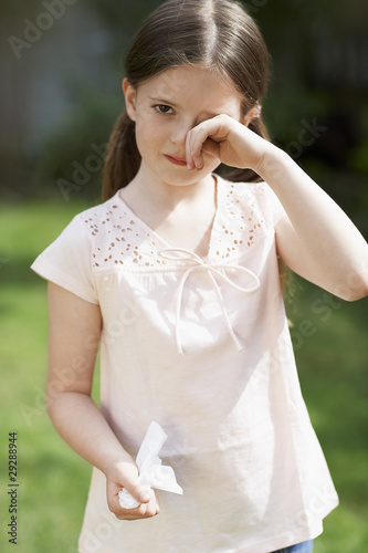 Photo: Little girl with cold rubbing eyes in backyard, portrait Little girl with cold rubbing eyes in backyard, portrait