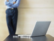 Businessman standing by laptop and Cell Phone on desk, focus on foreground