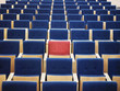 One Red Seat in large group of blue seats in auditorium