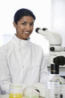 Female Asian lab worker standing by microscope
