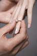 Man placing engagement ring on woman's finger, close-up of hands