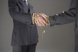 Businessmen shaking hands wrapped in gold chain with padlock, mid section