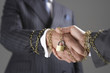 Businessmen shaking hands wrapped in gold chain with padlock, close-up of hands