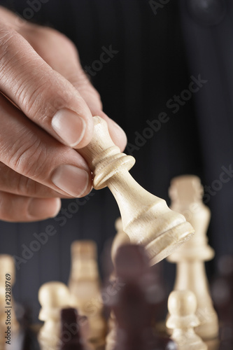 Photo: Man playing chess, close-up of hand holding piece Man playing chess, close-up of hand holding piece